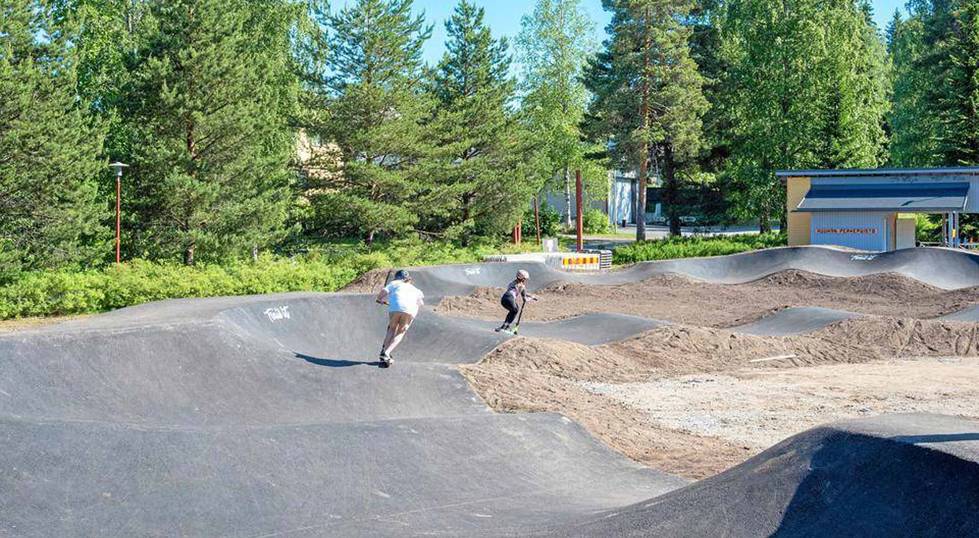 Lapset scooteilla Pump Track -radalla.