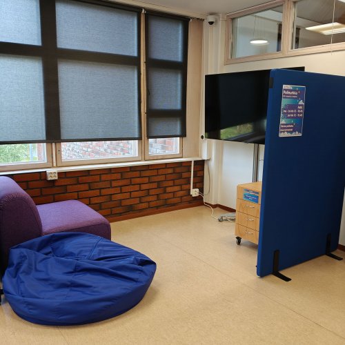 Kuva pleikkarinurkasta. Violetti nojatuoli, sininen säkkituoli ja televisio.