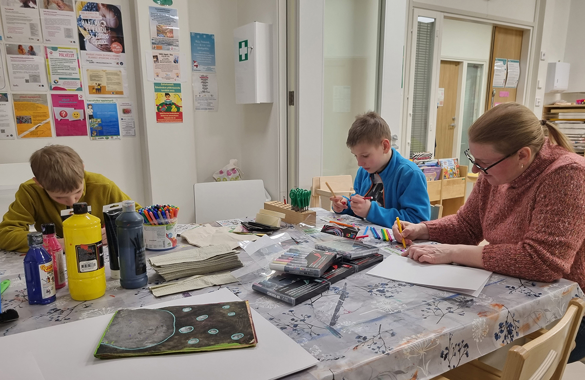 Maria Vdovets ja lapset Art&Play -taidekerhossa. – Tärkeintä on tarjota kävijöille luovaa tekemistä ja sosiokulttuurista innostamista. Täällä ei ole tarkoituksena mitään Mona Lisoja tehdä, ohjaaja Hannele Torniainen sanoo. 