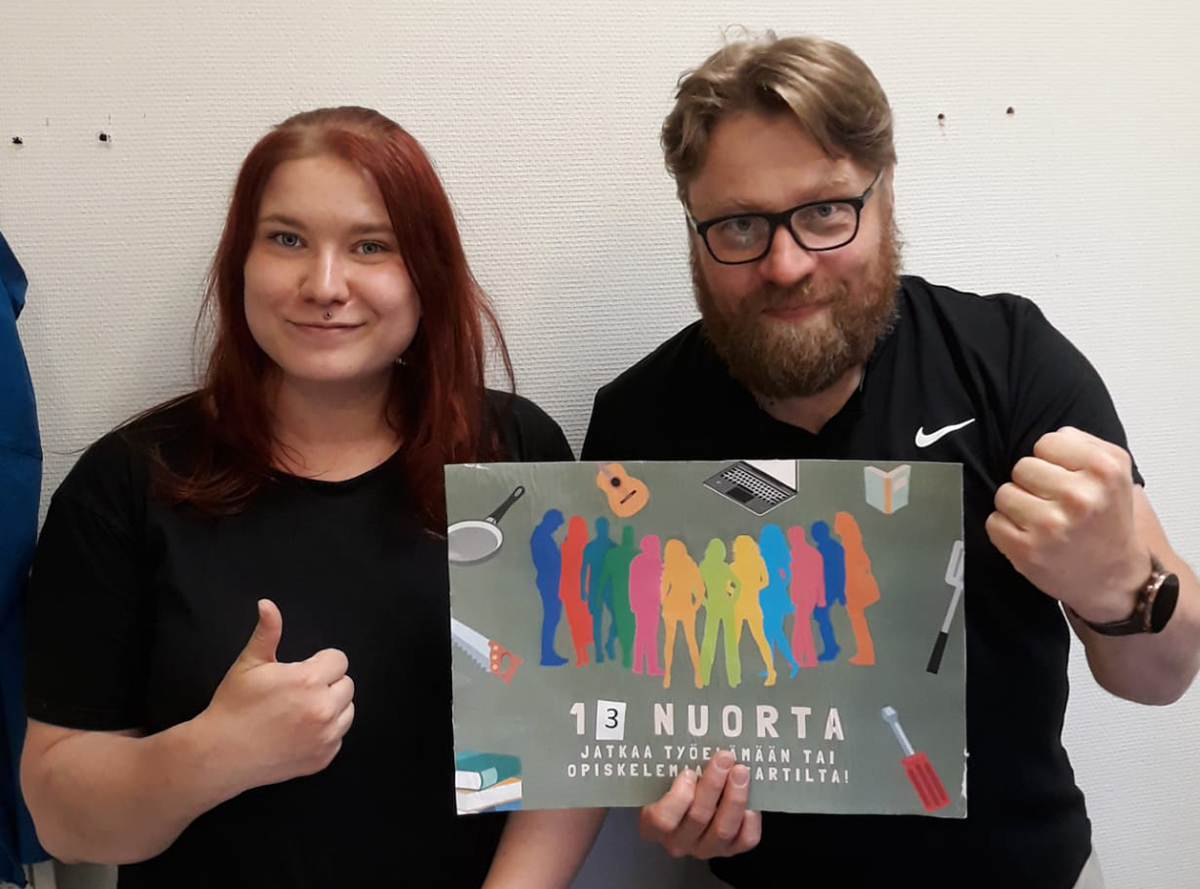 Nainen ja mies näyttävät kylttiä ja peukkua.