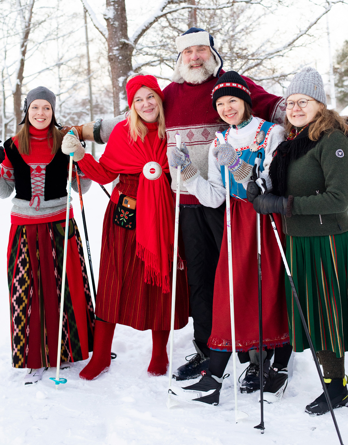 Naiset puvuissaan ja suksilla, keskellä Juha Mieto.
