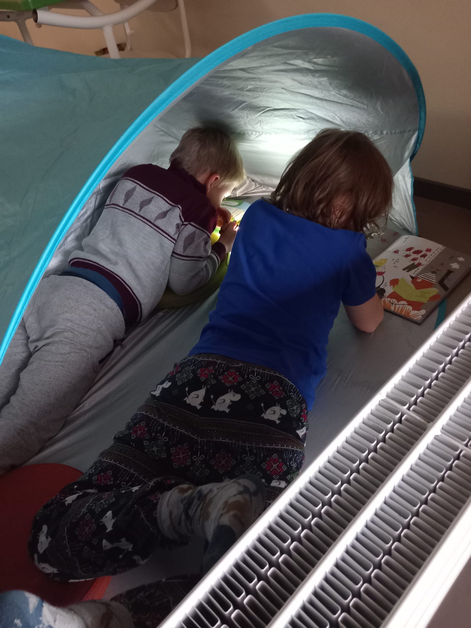 Lapset lukee teltassa.